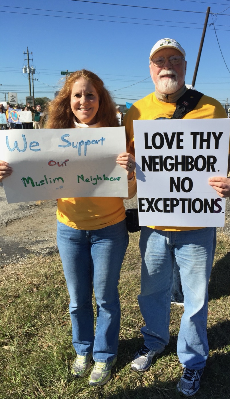 Terry and Clif holding signs that read &lsquo;We Support Our Muslim Neighbors&rsquo; and &lsquo;Love Thy Neighbor. No Exceptions.&rsquo;