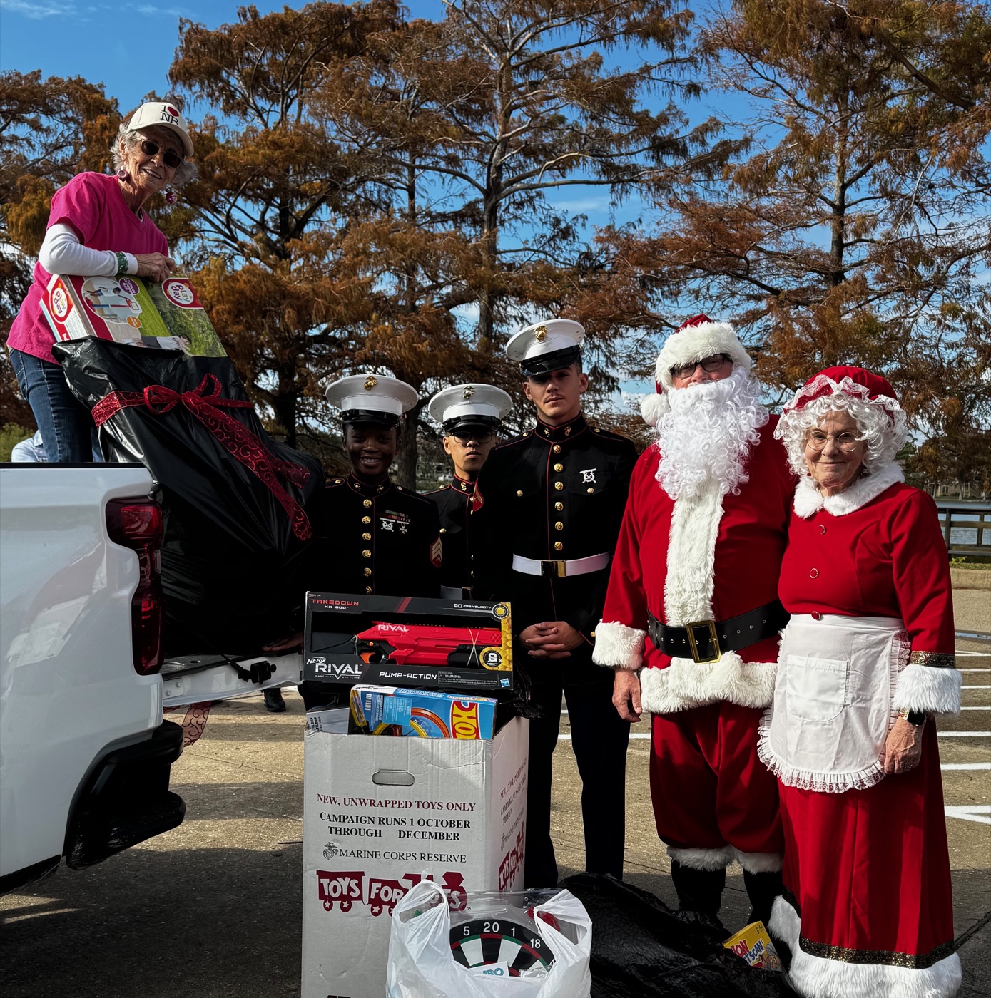 Terry loading donations into a pickup truck alongside two U.S. Marines and Santa and Mrs. Claus at a Toys for Tots drive.